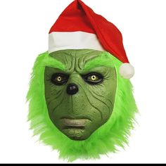 the grin face mask is green and has a santa hat on it's head