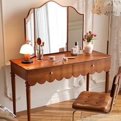 a dressing table with a mirror, stool and lamp in a room next to a window