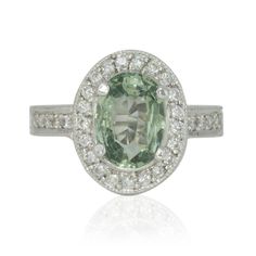 an oval shaped green and white diamond ring with diamonds around the band, set in 18k white gold