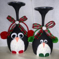 two black vases decorated with red and green decorations, one has a penguin face on it