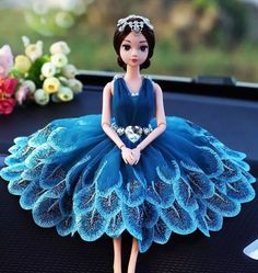 the doll is wearing a blue dress with feathers on it's skirt and tiara