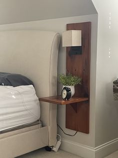 a bed with a wooden shelf next to it and a lamp on the side table