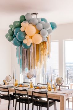 a dining room table with balloons hanging from it's ceiling and plates on the table