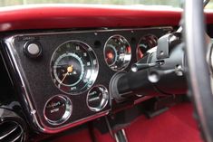 the gauges and dash board of an old car with red carpeting in front of it