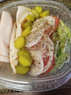 a plastic container filled with sliced up vegetables and meats on top of each other