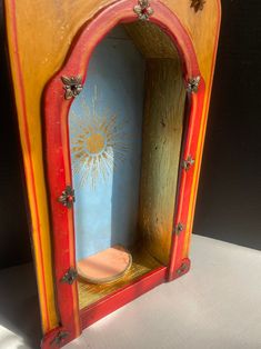 a small wooden cabinet with a toilet in the middle and sun painted on the side