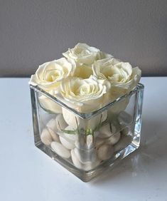 a clear vase filled with white flowers on top of a table