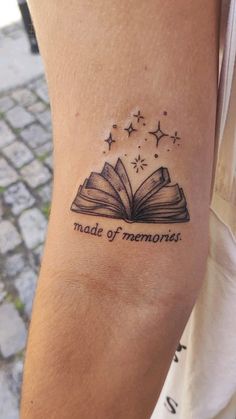 a person with a tattoo on their arm that says made of memories and an open book