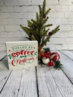 a small christmas tree sitting on top of a wooden table next to a sign that says fueled by coffee and christmas