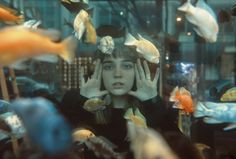 a woman with her hands on her head surrounded by fish