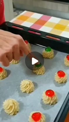 the person is making cookies with icing and cherries