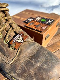 an old pair of brown work boots sitting on top of a wooden table next to a box