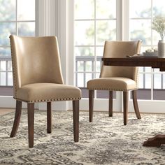 two chairs sitting on top of a rug in front of a dining room table and windows