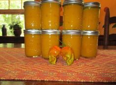 several jars filled with yellow liquid sitting on top of a table next to an orange pepper