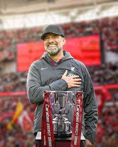 a man standing in front of a trophy on top of a field