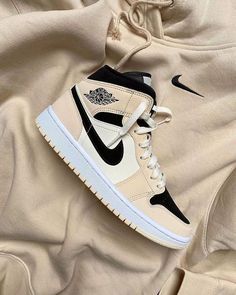 the nike air jordan 1 mid sneaker is on top of a beige sweatshirt with black and white accents