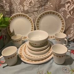 a table topped with lots of white dishes and cups next to a potted plant