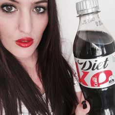 a woman holding up a diet coke bottle with red lipstick and black eyeliners