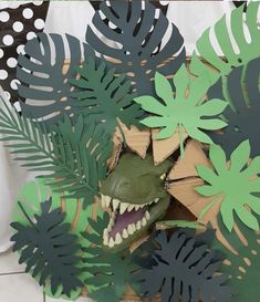 there is a paper cut out of leaves and a dinosaur head in the middle of it