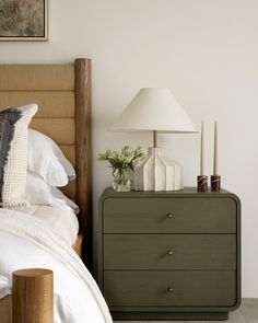 a bedroom with a bed, night stand and lamp on the nightstand next to it