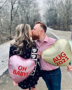 a man and woman kissing while holding balloons