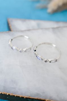 It's all in the details and this ring has it all figured out. This dainty rainbow moonstone ring set in 925 sterling silver, is ready to fit right into your stack. Its horizontal marquise stones between two dainty round stones give it dimension and a unique look, while still staying minimal and simple. Make it a matching set with the 'Olivia Earrings' to complete your look! 925 Sterling Silver Genuine Rainbow Moonstone Stone Size 3mm x 6mm marquise and 2mm round Nickel Free Hypoallergenic Rainbo Moonstone Properties, Pop Up Market, Ring Moonstone, Moonstone Stone, Rainbow Moonstone Ring, Moonstone Ring, Modern Jewelry, Rainbow Moonstone, Ring Set