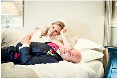 a man and woman laying on top of a bed in their wedding day attire, posing for the camera