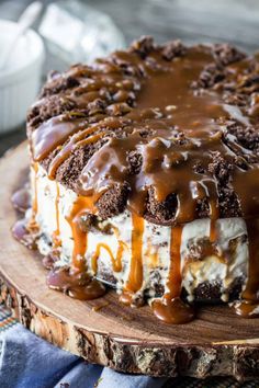 a cake covered in ice cream and caramel drizzle on a wooden platter