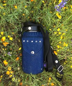 a blue cell phone case sitting on top of a field of grass and wildflowers