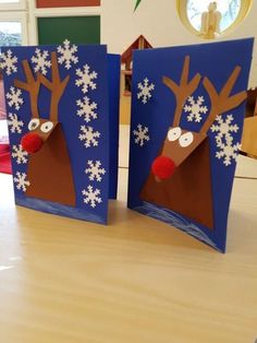 two cards with reindeer faces on them sitting on a table