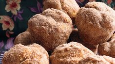 a pile of sugared donuts sitting on top of a metal rack next to a floral wallpaper