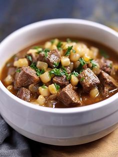 a close up of a bowl of food with meat and corn in it on a table