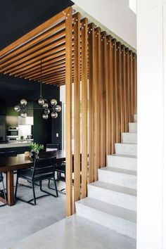 a dining room and kitchen area with wooden slats on the wall, stairs leading up to an open floor plan