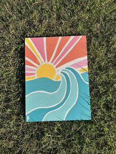 a piece of art that is laying on the ground in the grass with water and sun painted on it