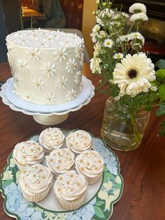 cupcakes and a cake on a table with flowers