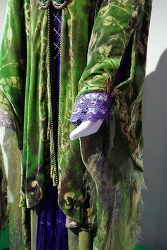 a green and purple outfit on display in front of a white wall