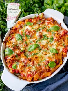 a casserole dish with cheese, tomato sauce and fresh basil leaves on top