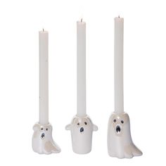 three white candles with ghost faces on them and one candle in the shape of a ghost