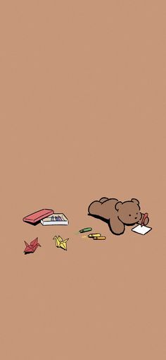 a brown teddy bear laying on top of a floor next to papers and origami