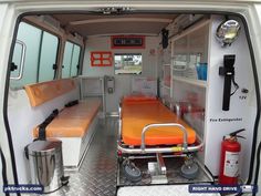 the inside of an ambulance with two beds and orange sheets on it's sides