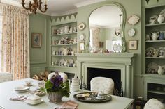 a dining room table with plates and cups on it next to a fire place in front of a fireplace