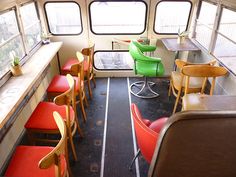 the inside of a bus with red seats and green chairs on either side of the windows