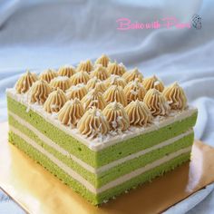 a green and white layered cake on a gold platter, with frosting in the middle