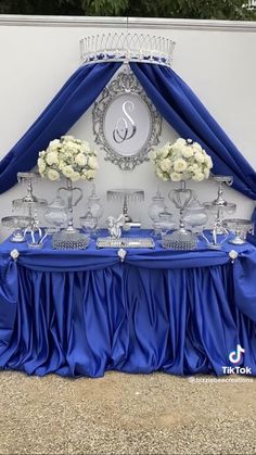 the table is covered with blue cloths and white flowers