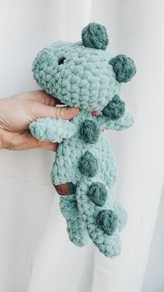 a person holding a crocheted stuffed animal in their left hand and the other hand is holding it up