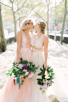 two women standing next to each other in front of trees