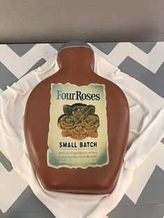 a bottle shaped cake sitting on top of a white tablecloth covered plate with an advertisement for four roses small batch