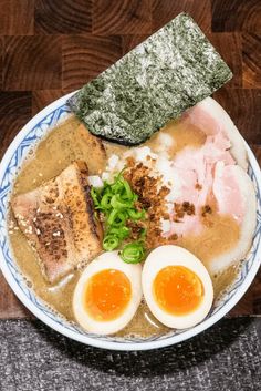 a bowl filled with different types of food on top of a wooden table next to chopsticks