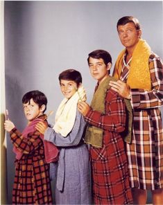 three men in plaid robes standing next to each other, one holding a towel and the other looking at the camera