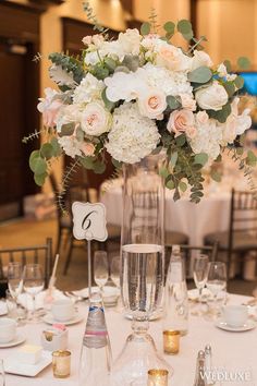 a tall vase filled with pink and blue flowers on top of a dining room table